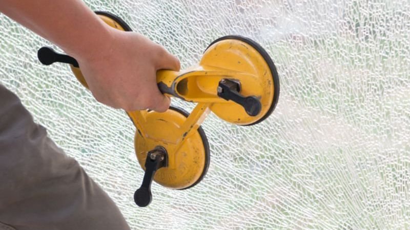 A person employs a yellow tool to clean a window, highlighting the process of glass repair and restoration.