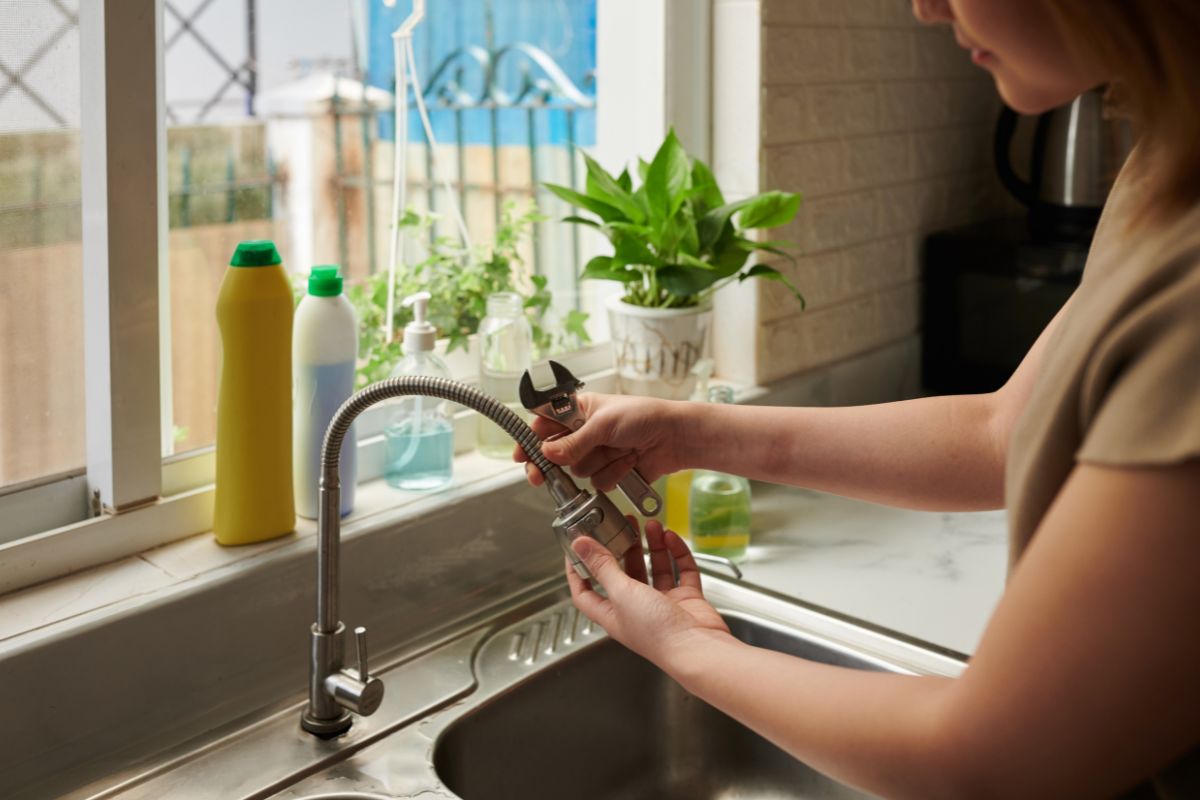  A woman diligently cleans a kitchen sink, ensuring a spotless and hygienic workspace.