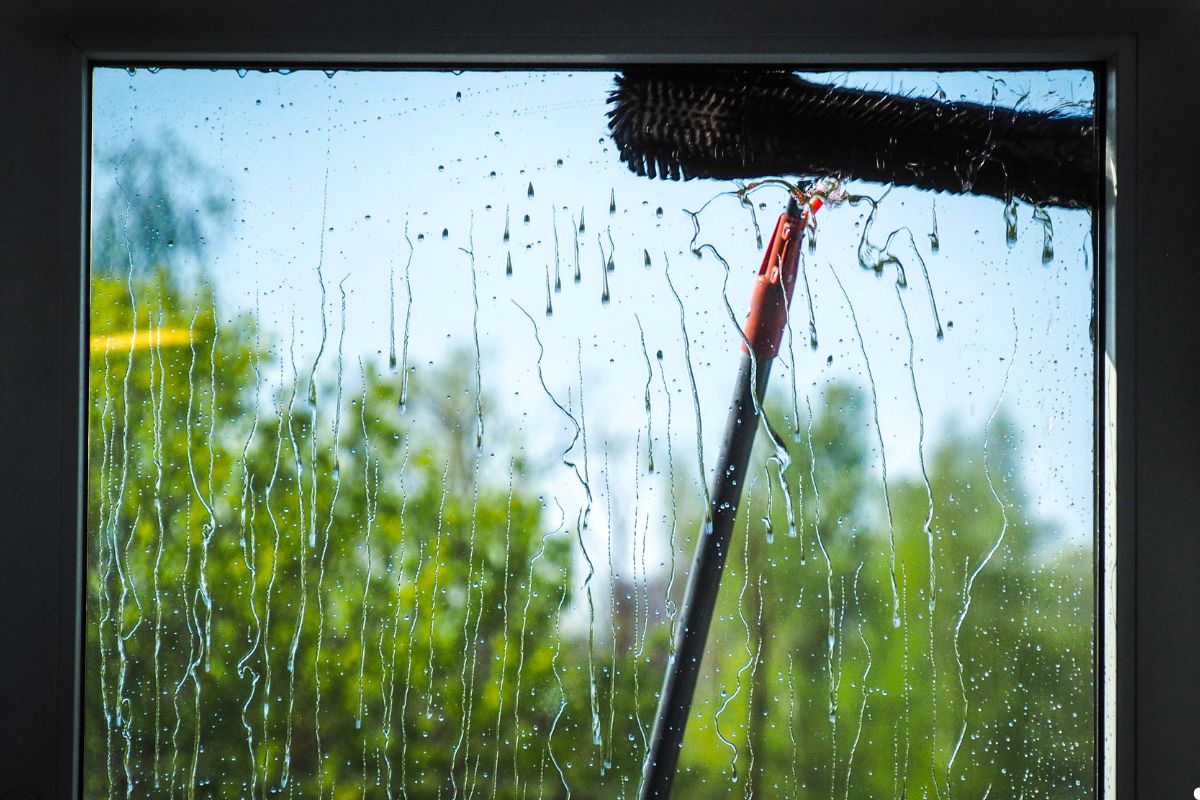 A window being cleaned by a professional window cleaner using a squeegee and cleaning solution.