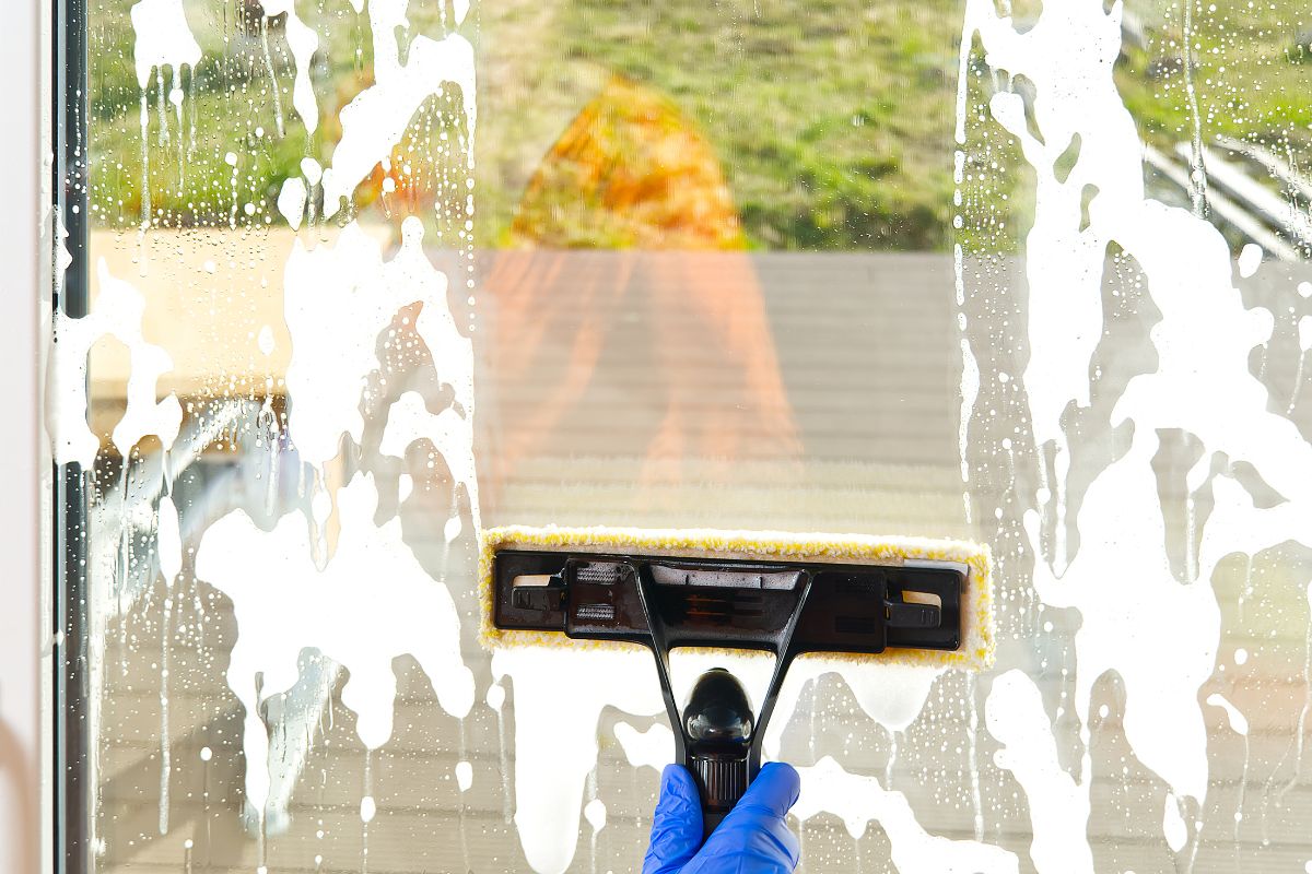 A person cleaning a window with a squeegee, demonstrating effective window maintenance techniques.