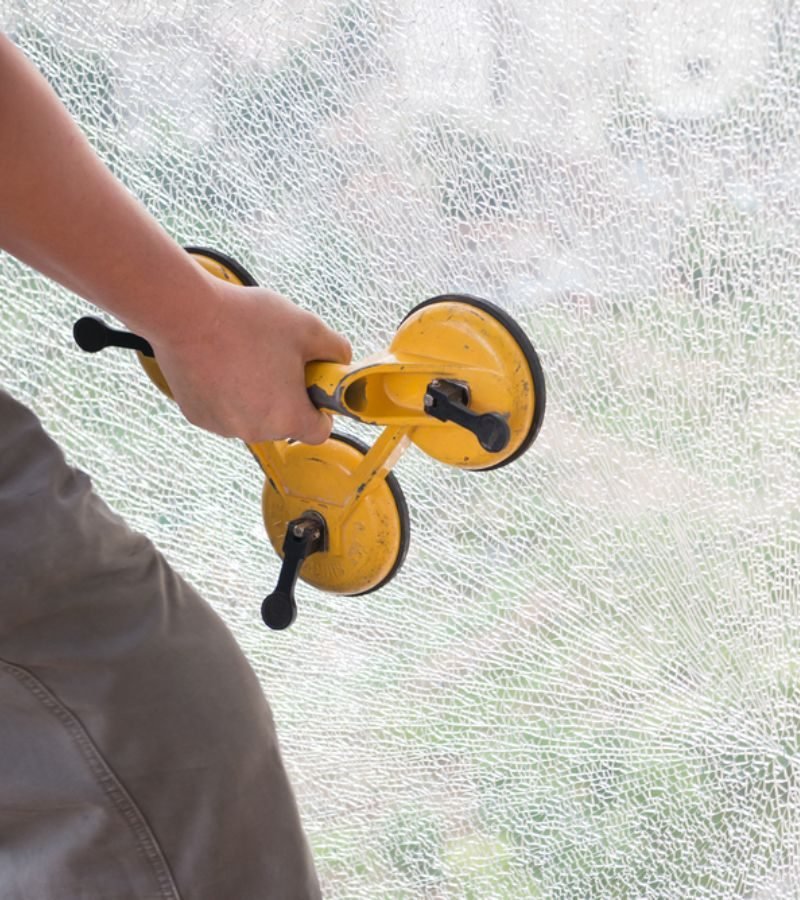 A person employs a squeegee to clean glass, showcasing the work of a glass repair and restoration service.