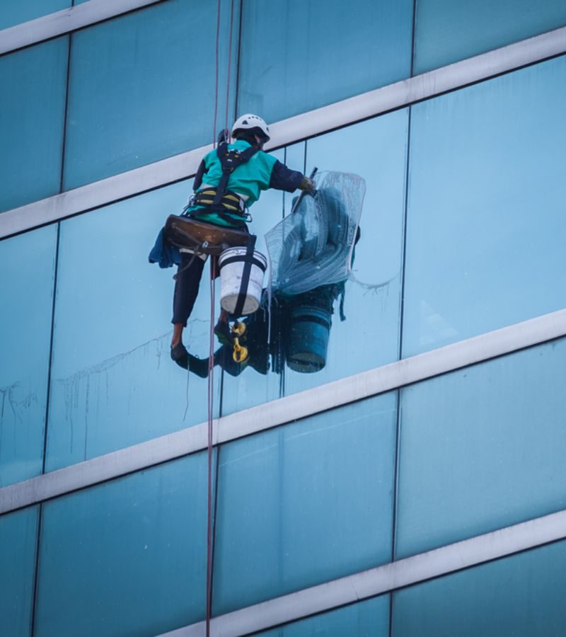 A man in a safety vest cleans windows, illustrating the dedicated service provided by Storm Window Cleaning Service.